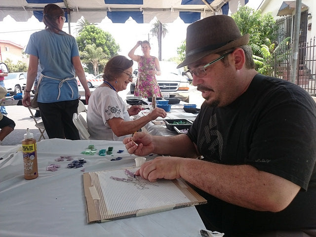 An artist working outside on a mosaic during a Piece by Piece workshop.