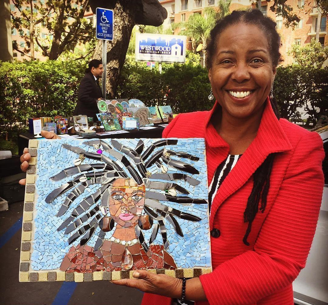 Artist holding a mosaic portrait of a woman.