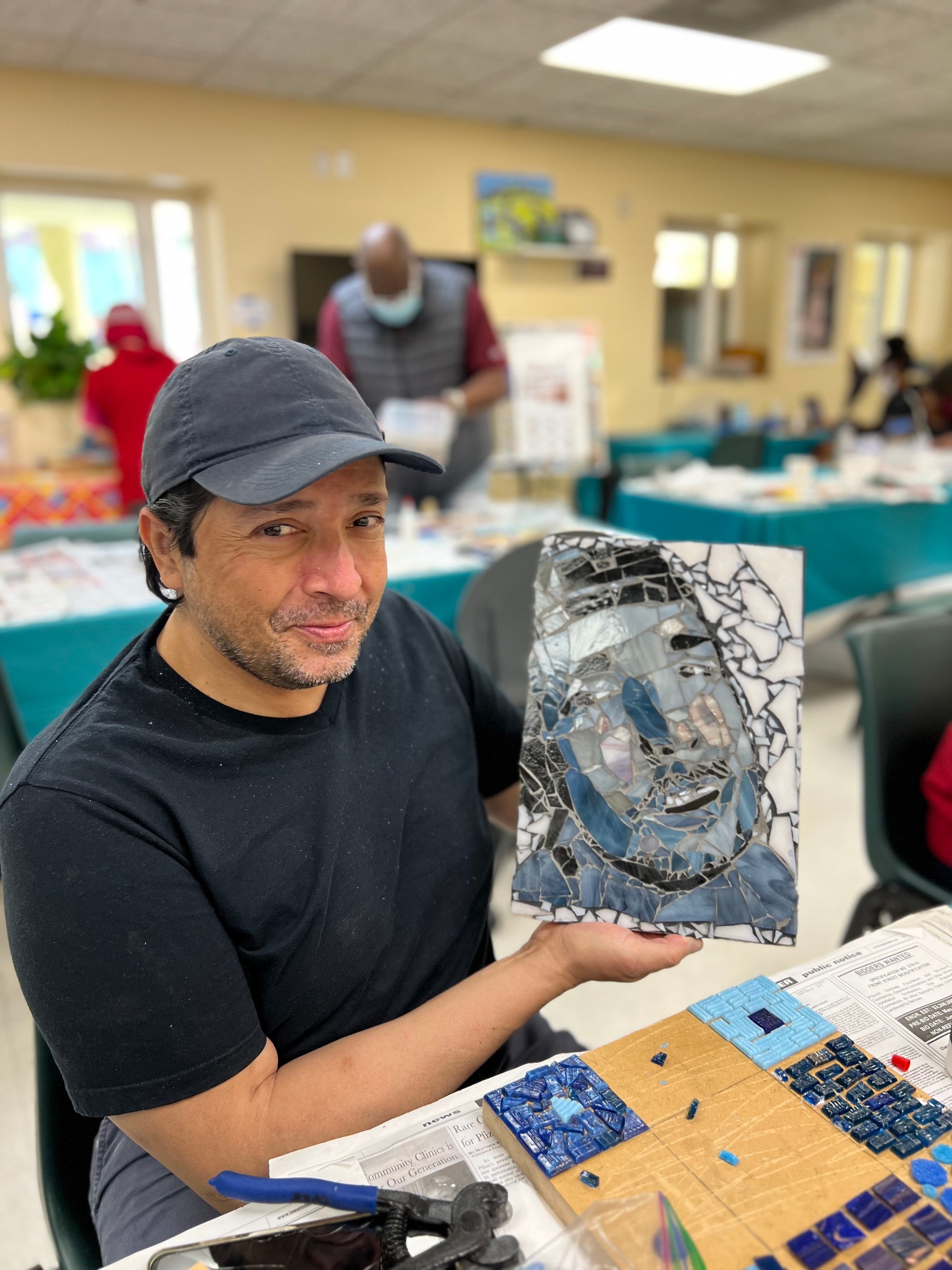 Artist holding up a self-portrait mosaic.